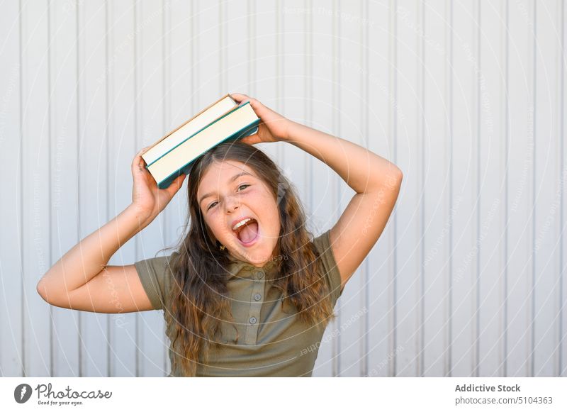 Joyful student with books screaming against wall girl knowledge excited portrait happy cheerful education carefree mouth opened schoolgirl textbook expressive