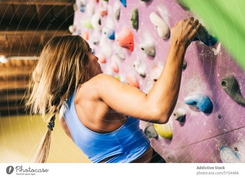Unrecognizable female athlete on climbing wall sportswoman grip gym training bouldering strong tilt effort grasp hang activity extreme challenge stamina