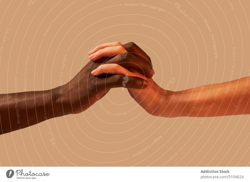 Unrecognizable multiracial couple holding hands together tender tolerance unity contrast relationship studio bonding diverse man woman romantic multiethnic