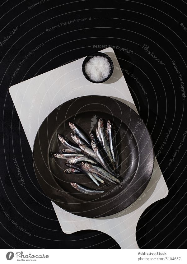 Raw small fishes in plate on dark background asian food sardine omega three meal italian tasty seafood anchovy uncooked mediterranean anchovies