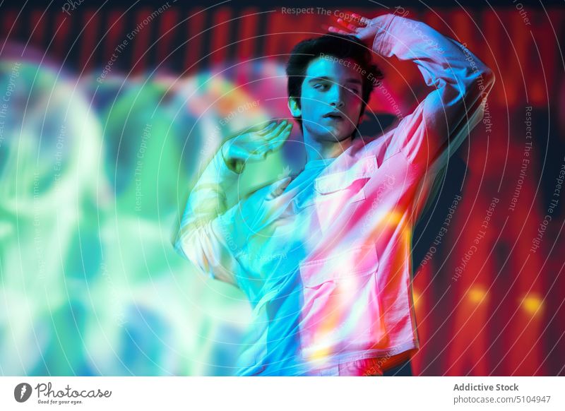Modern man standing in neon lights model studio shot eyes closed multicolored illuminate individuality projector emotionless art unemotional male futuristic