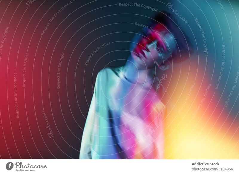 Young dancer man profile in neon illumination model multicolored light studio shot individuality eyes closed perform emotionless unemotional male young luminous