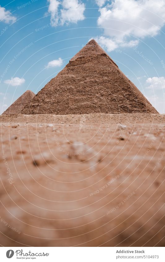 Ancient Egyptian pyramids in desert on sunny day heritage monument sightseeing wonder culture tourism landmark ancient historic complex cloudy blue sky arid