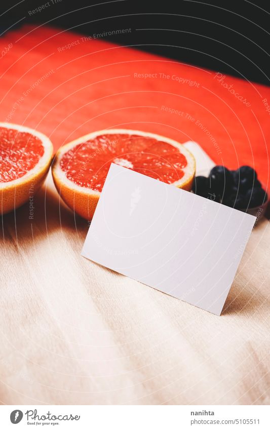 Mockup of a business card in vibrant tones near to fresh fruit grapfruit and blueberries mockup organic background paper grapefruit blueberry color red orange