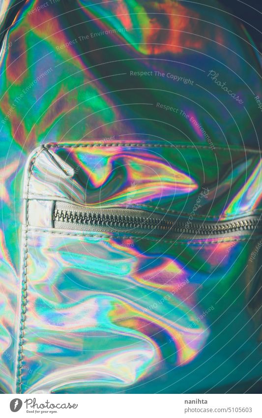 Detail of an holographic and iridiscent school bag rainbow background zipper pocket accessories fashion trendy fresh cool youth youthful punk aesthetic
