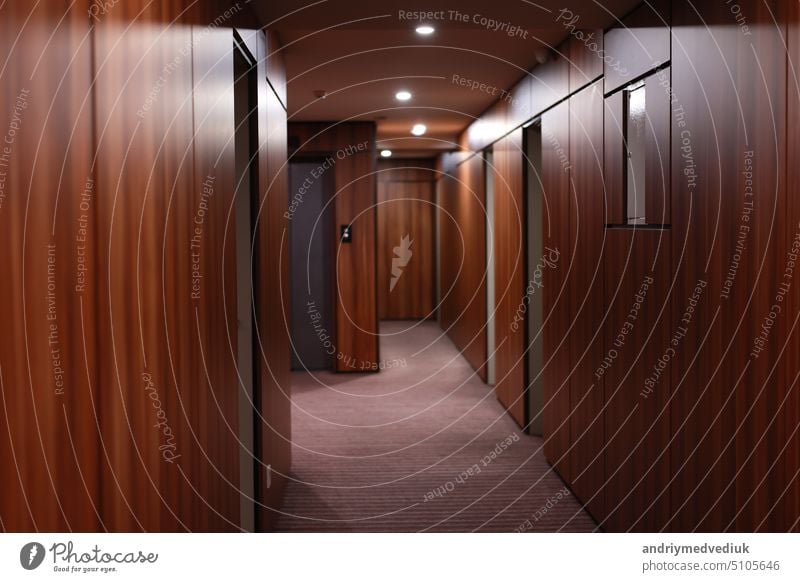 Empty dark interior of the modern Hotel corridor, with wood-paneled walls, elegant carpets and lighting on the ceiling. hotel door empty room floor indoor hall