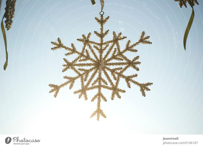artificial snowflake hanger from beads Snow Star Decoration cold season View from a window blue sky background Winter sparkle Back-light chill inboard