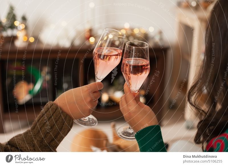 Two glasses of rose champagne in hand to toast Christmas or New Year. Celebrating at a party. Happy birthday or anniversary. Festive drinks background. Parties and celebrations. Cheers with glasses. Horizontal new year party background.