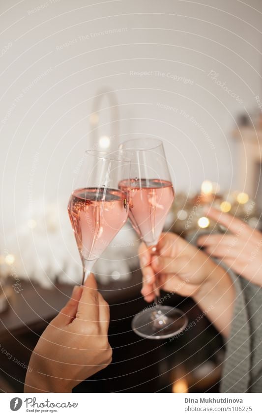 Holding two glasses of rose sparkling wine to cheers for Christmas or New year. Celebrating at party. Happy Birthday or anniversary. Festive drinks background