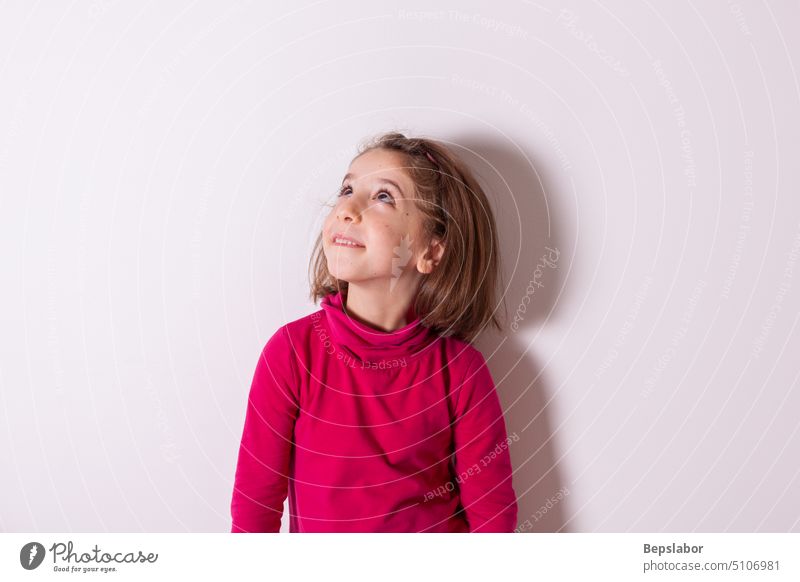 Little child girl smiling and looking up on white background joy smile person happy cute elementary kid student youth face female fun little young childhood