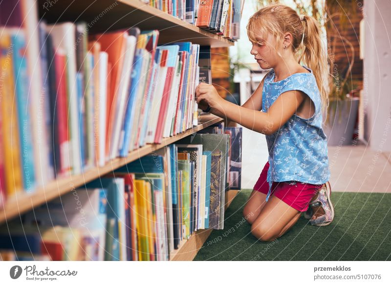 Schoolgirl looking for book for reading in school library. Student selecting literature for reading. Books on shelves in bookstore. Learning from books. Back to school