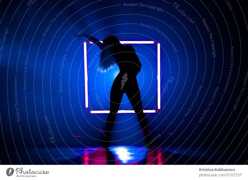 Silhouette of sexy woman dancing on glowing square of led lamps background. She looks seductively. Sexy outfit . Blue smoky studio. dancer female young slim