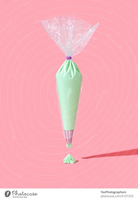 Frosting bag isolated on a pink background. Green buttercream icing in a plastic bag abstract baking banner bright candy celebration christmas color concept