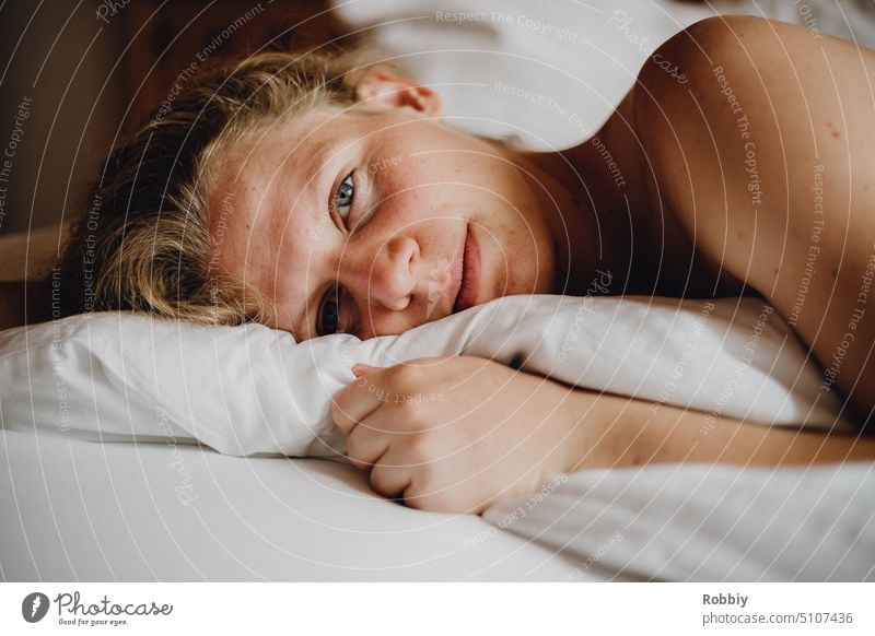 young blonde woman looking at camera lying in bed Sleep go to sleep Elegant Alluring Woman's body being a woman Body consciousness Beauty & Beauty sensuality