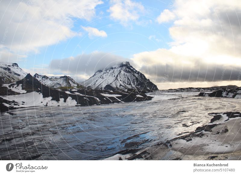 A hint of blue sky reflected in the meltwater of the Mýrdalsjökull glacier in Iceland with snow-capped mountains. Mountain Snowcapped peak Peak Melt water