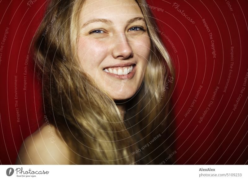 Close portrait of young blonde woman smiling in front of red background Woman Young woman Blonde Long-haired Smiling Joy Slim kind Pleasant pretty Attractive