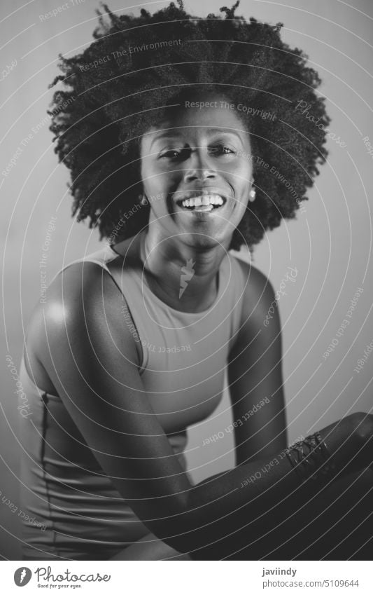 Black and white photograph of cheerful black model looking at camera woman style neon illuminate smile happy bright portrait female young african american
