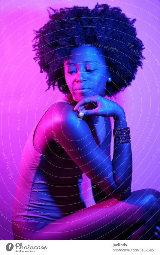 African American model under neon illumination woman touch chin sensual violet light slim appearance bodysuit illuminate female black african american ethnic