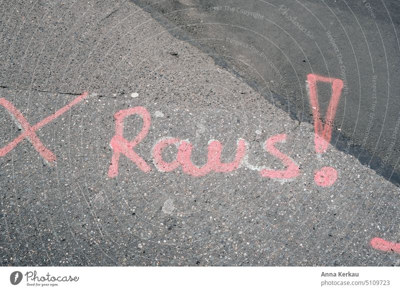 Pink lettering RAUS ! on asphalt Street art Street painting Command Assignment Classification imperative order Asphalt street art out Nose full writing