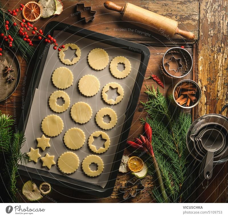 Christmas cookie preparation with baking sheet, rolling pin, fir branches and winter spices on wooden background, top view christmas tradition dough table