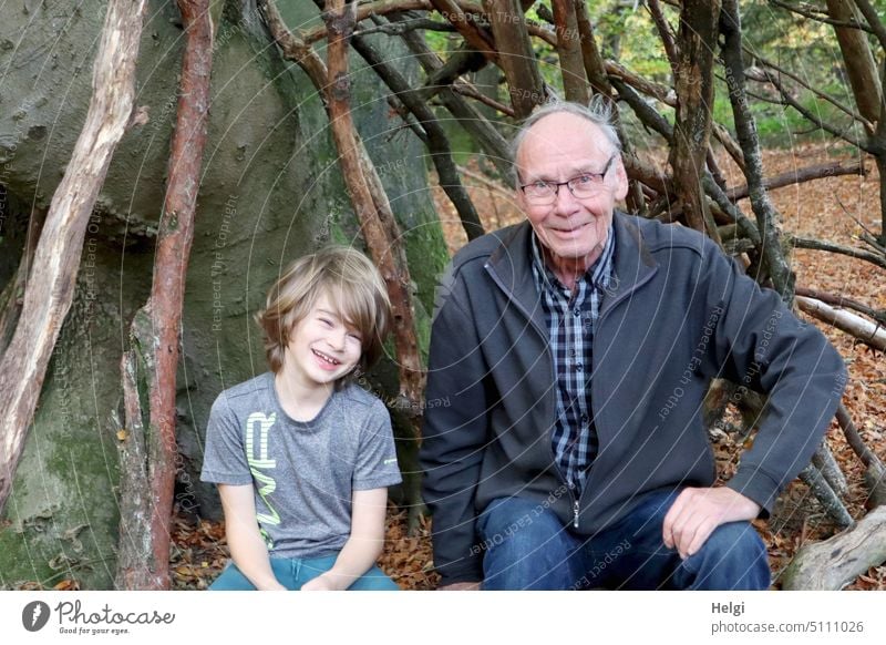 Grandpa and grandson sitting happily in forest in teepee made of branches Human being Child Schoolchild Boy (child) Man Senior citizen Grandfather grandpa