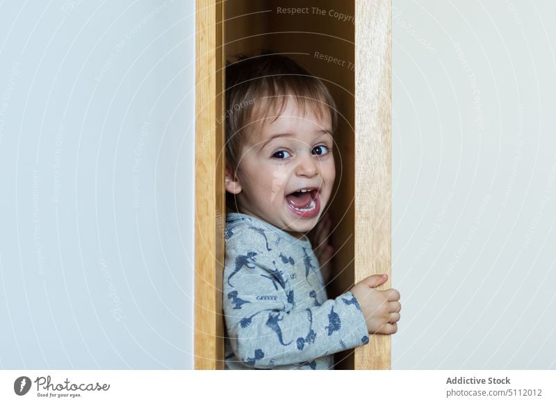 Funny boy squeezing through door funny squeeze wall scream wardrobe playful cute home child pajama mouth opened doorway excited adorable shout childhood