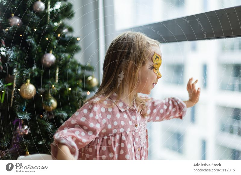 Girl looking out window on Christmas day girl christmas home curious touch glass christmas tree wait celebrate holiday festive child december interest childhood