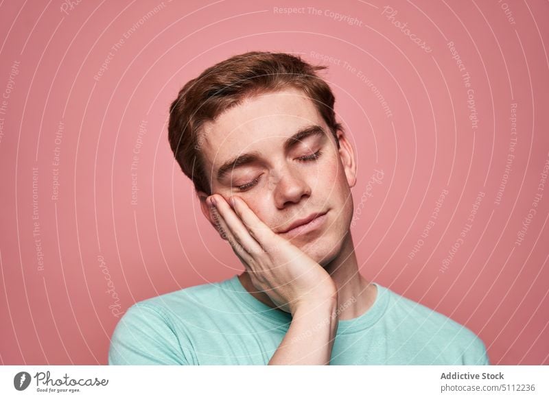 Young man touching cheek and sleeping touch cheek calm eyes closed pretend rest quiet colorful bright male young touch face hand on cheek nap model asleep
