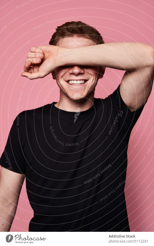 Happy young male covering eyes man cover eyes smile happy blind model modern casual colorful bright arm raised t shirt gesture cheerful positive vivid content