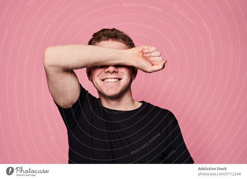 Happy young male covering eyes man cover eyes smile happy blind model modern casual colorful bright arm raised t shirt gesture cheerful positive vivid content