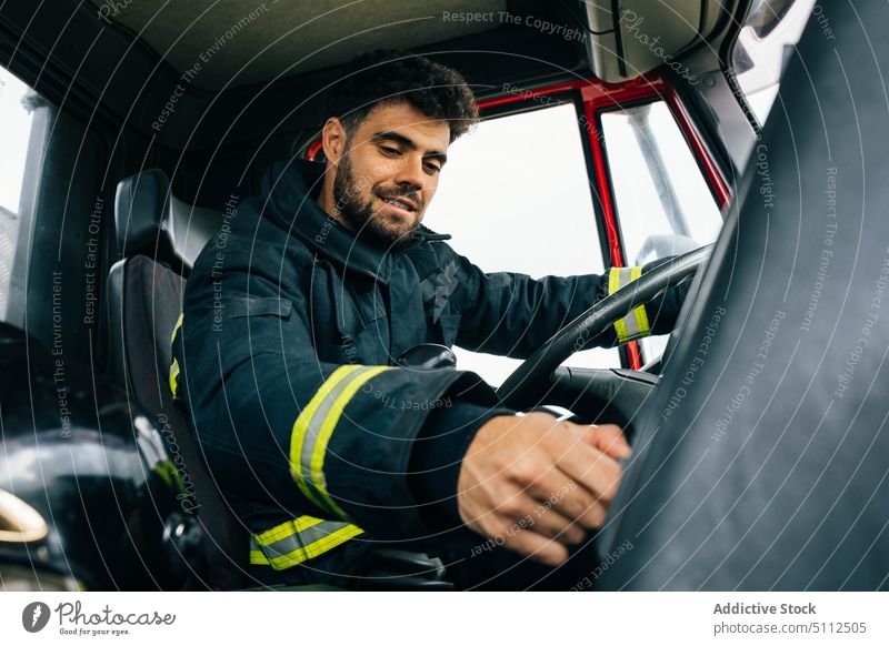Fireman driving fire engine in daytime fireman drive smile control press button dashboard work rescue male adult hispanic ethnic emergency uniform professional