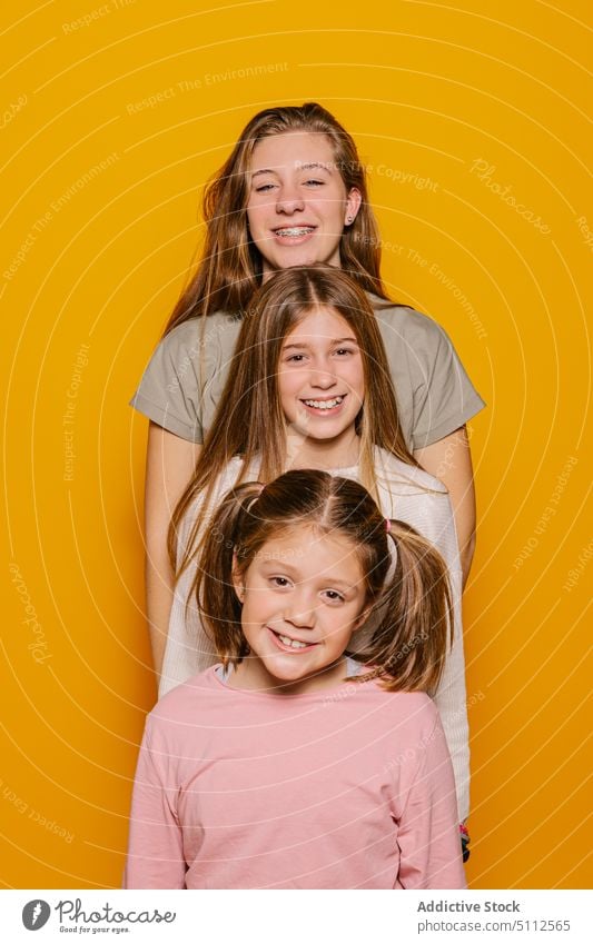 Cheerful sisters looking at camera happy cheerful together smile kid joy child positive girl bright excited colorful glad casual optimist young fun delight