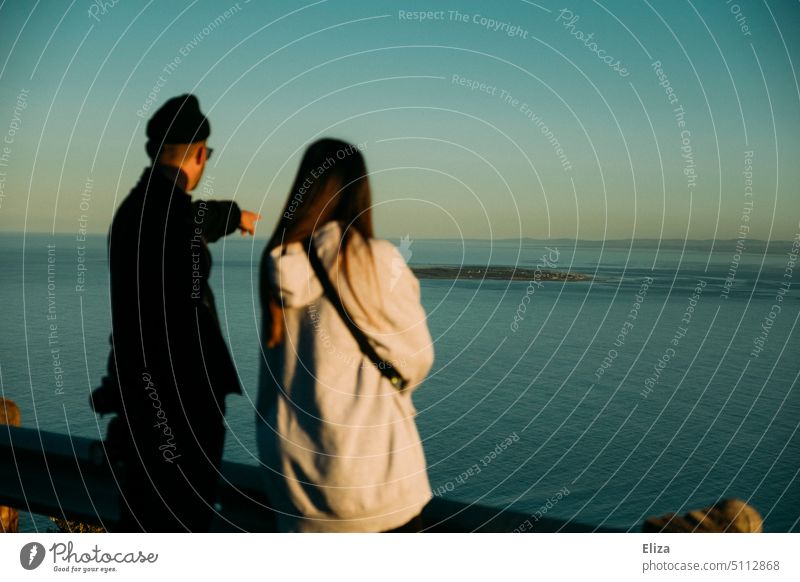 Couple on vacation, man pointing to sea Ocean Indicate Blue two Observe Water people Black Vacation & Travel wide Horizon coast Nature Far-off places Adventure