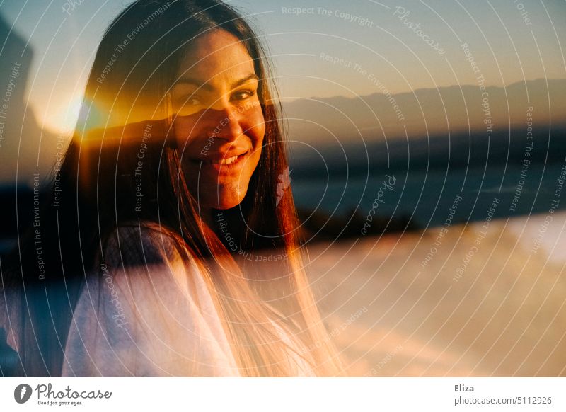 Double exposure of smiling woman with a sunrise Woman Optimism Sunrise portrait Dark-haired rays Young woman Looking into the camera Far-off places pretty warm