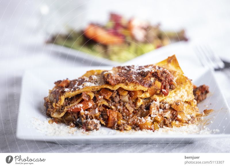 Portion of lasagna on a white plate Lasagne Cheese Mozzarella Parmigiano Italian pasta Tomato background Bolognese Meat Meal Italy boil vegetarian Vegetable