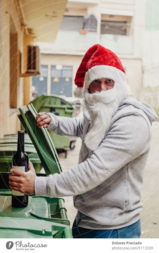 Homeless Santa drinking wine and rummaging through garbage bins alcohol alcoholic bad santa beard begging bottle brutal caucasian celebration charity christmas