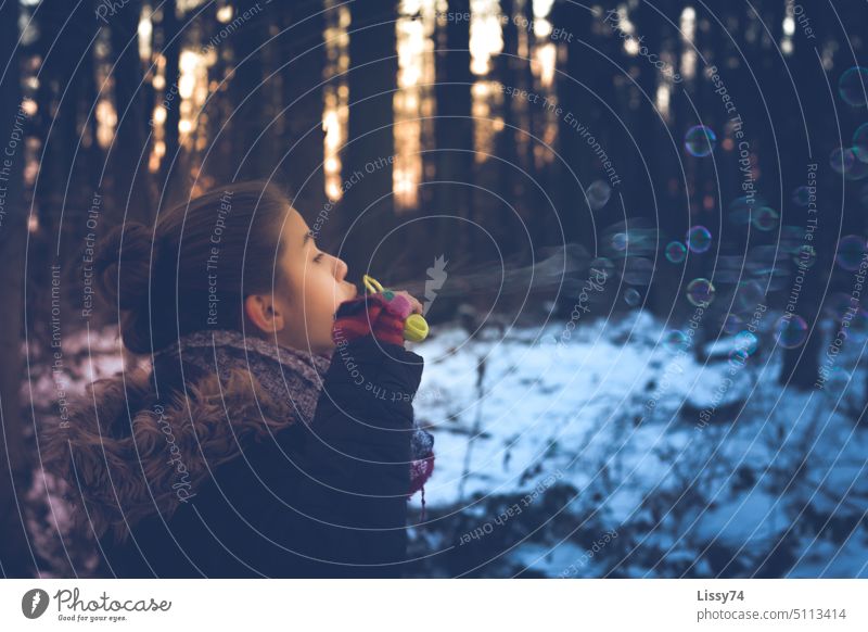 Girl blowing soap bubbles in winter forest Child Infancy fun Joy Winter Snow Childhood memory Evening sun Forest trees Recording Colour photo