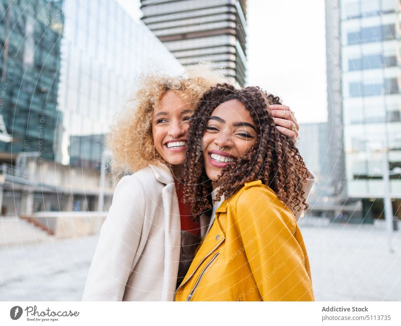 Smiling cool diverse ladies standing on street women friend smile city style cheerful embrace positive portrait together spend time young multiracial