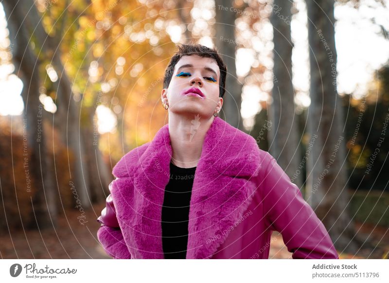 Androgynous man with makeup standing in autumn park androgynous forest self assured lgbt transsexual non binary tree portrait homosexual gender confident male
