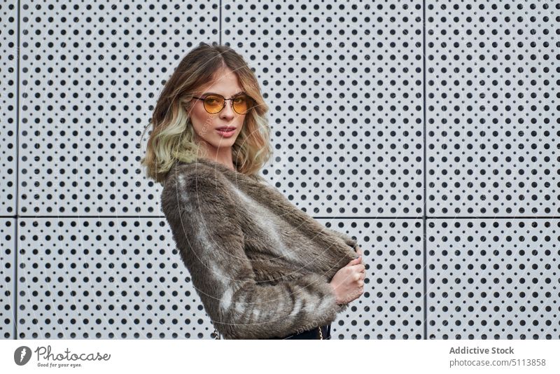 Self assured young lady in sunglasses and looking at camera woman style confident individuality portrait street self assured wavy hair blond faux fur human face