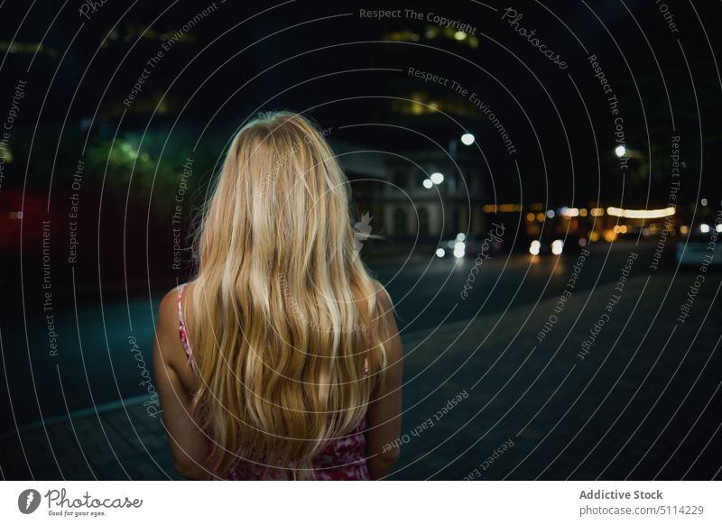 Anonymous blond woman on street at night dark long hair alone style sidewalk nightlife female urban road party event town evening way dim obscure stand avenue