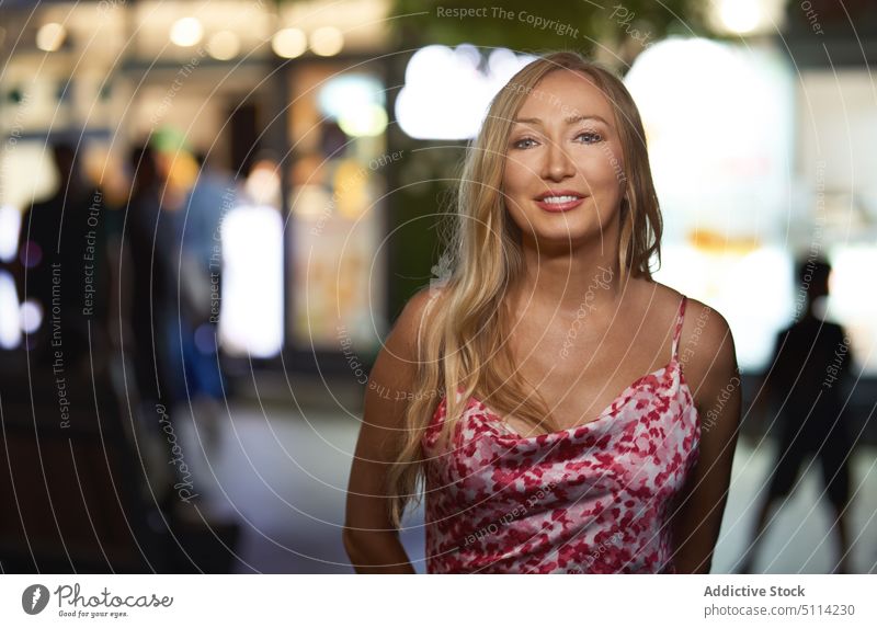 Cheerful young woman looking at camera on the street smile night happy urban portrait style nightlife female evening cheerful blond positive glad dress optimist