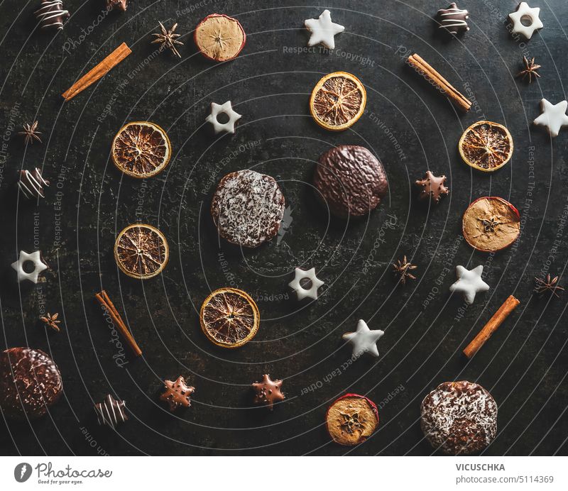 Christmas pattern made with dried orange, cinnamon sticks, gingerbread and Christmas cookies on dark kitchen table background. Top view. christmas