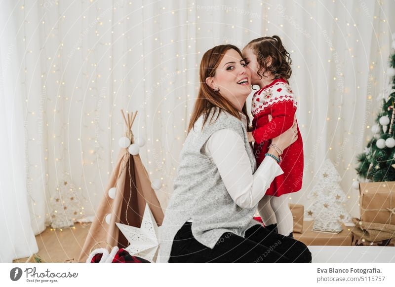 cute child kissing mother. enjoying christmas time at home family daughter living room love together motherhood single mother caucasian celebration happy