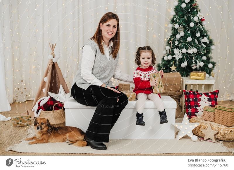 happy mother and daughter at home during christmas time. child holding presents family living room love together motherhood single mother caucasian celebration