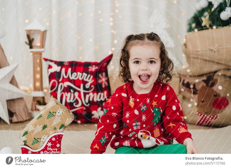 cute smiling little girl at home holding presents during christmas time child happy gift cheerful 2 kid children family december decoration indoors smile