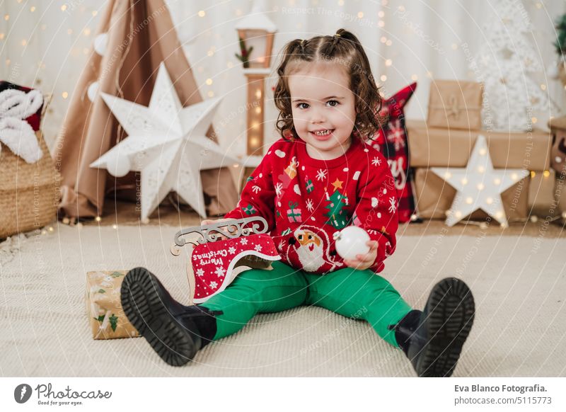 happy little girl at home holding presents during christmas time child gift cheerful cute 2 kid children family december decoration indoors smile adorable star