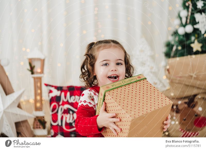 cheerful little girl at home during christmas time holding gift box child presents happy cute 2 kid children family december decoration indoors smile adorable