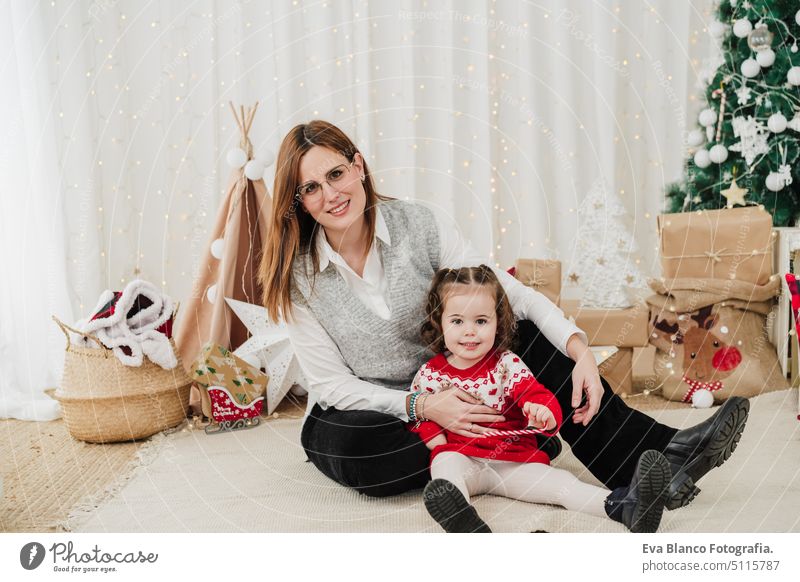 happy mother and daughter embracing at home during christmas time family living room love together motherhood single mother caucasian celebration child indoors