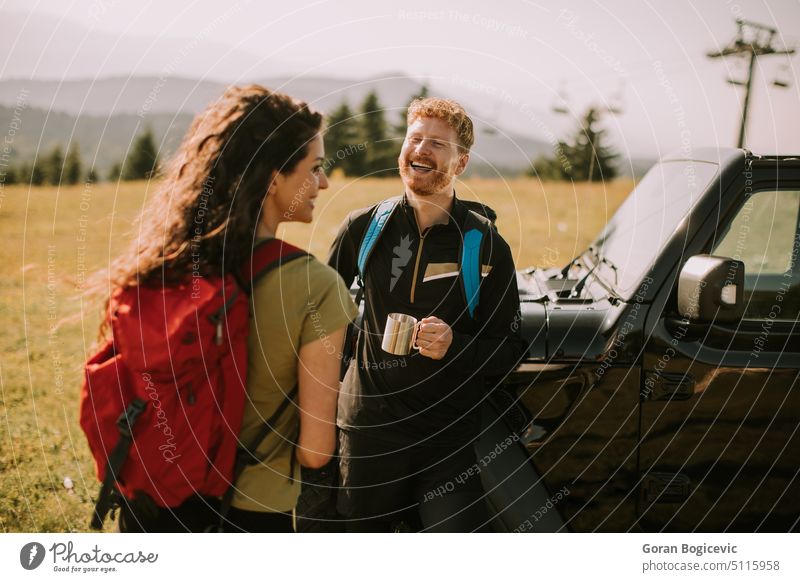 Smiling couple preparing hiking adventure with backpacks by terrain vehicle active activity adults backpacker backpacking boyfriend car caucasian countryside